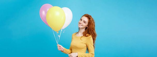 Close-up portret gelukkig jonge mooie aantrekkelijke redhair meisje glimlachend met kleurrijke partij ballon. Blauwe Pastel achtergrond. - Foto, afbeelding