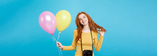 Estilo de vida e conceito de festa - Close up Retrato jovem bonita atraente ruiva menina de cabelo vermelho com balão colorido e câmera vintage. Fundo Pastel Azul. Espaço de cópia
 - Foto, Imagem