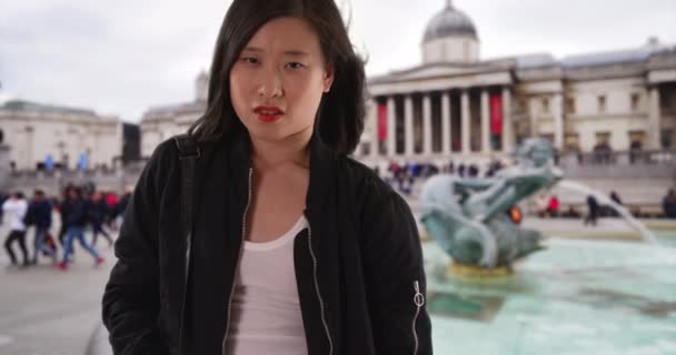 Londra 'da tatilde elleri ceplerinde siyah bombacı ceketi giyen Çinli bir kadın. Asyalı milenyum turisti İngiltere 'de tatilde. 4k - Video, Çekim