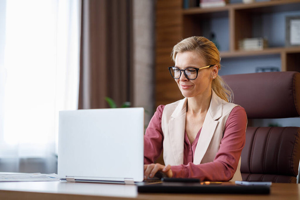Portrait of beautiful businesswoman working with laptop at office. Texting messages, browsing internet, studying online, remote working. Business concept. Portrait of modern successful female leader. - Foto, immagini