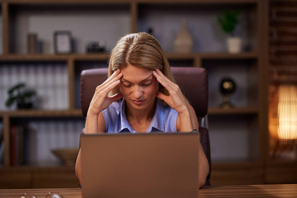 Exhausted woman feels eye fatigue after using laptop. In stress, an overworked woman takes off her glasses and massages her irritated eyes. Overworking, burnout. - Foto, immagini