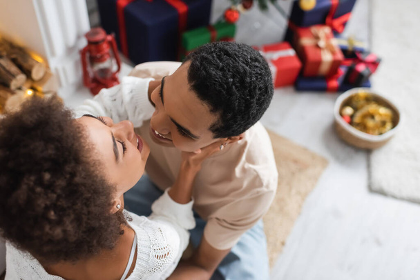 overhead view of happy african american couple embracing at home on christmas day - Fotografie, Obrázek