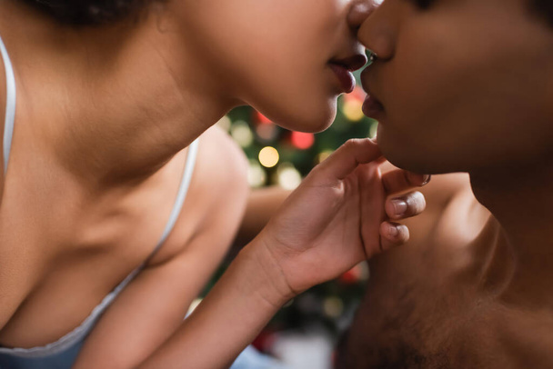 partial view of sexy african american woman kissing boyfriend on christmas eve - Photo, Image