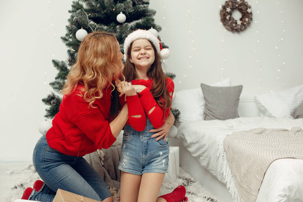 Az emberek helyrehozzák a karácsonyt. Anya játszik a lányával. A család egy ünnepi szobában pihen. Gyerek piros pulcsiban.. - Fotó, kép