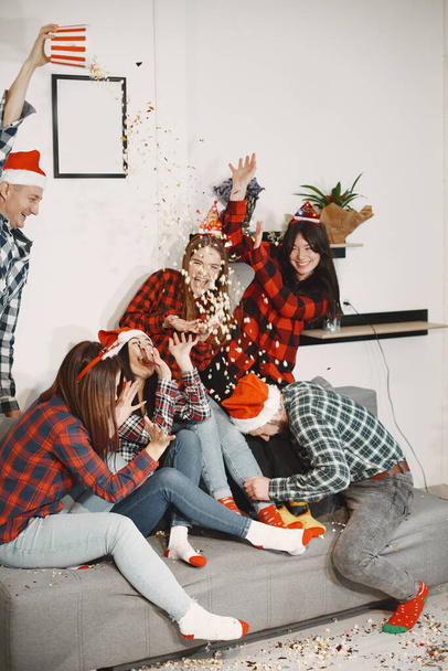 Onnellinen ryhmä nuoria puolueessa. Ihmiset juhlivat joulua ja uutta vuotta. Ystävät kotona popcornin kanssa. - Valokuva, kuva