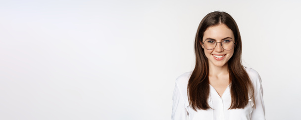 Close up portrait of smiling girl entrepreneur, office woman in glasses, looking happy and confident, standing in white blouse over studio background. - Fotoğraf, Görsel