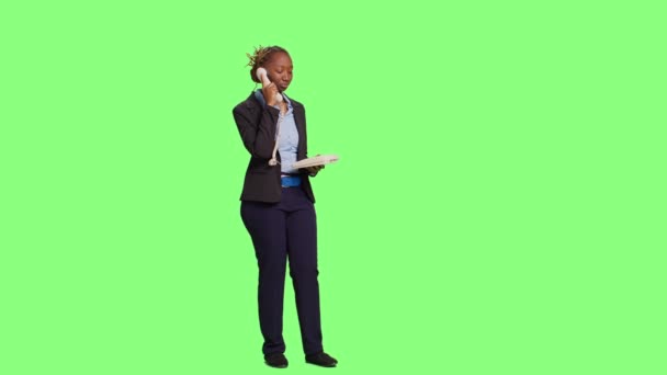 Company employee talking on landline phone call in studio, answering office telephone with cord on full body greenscreen backdrop. Business woman acting friendly over background. - Footage, Video