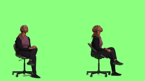 Positive fröhliche Mädchen sitzen auf Stuhl in zwei Seiten der Ganzkörper-Greenscreen-Hintergrund, warten und vorbereiten. Ungeduldige Frau sitzt auf einem Hocker und wartet auf die Vorbereitung, grüner Hintergrund. - Filmmaterial, Video