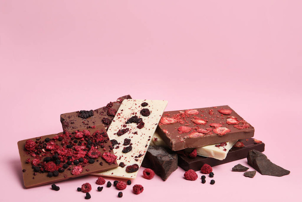 Different chocolate bars with freeze dried fruits on pink background, space for text - Фото, зображення