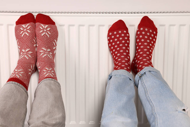 People warming feet near heating radiator, closeup - Foto, Imagem