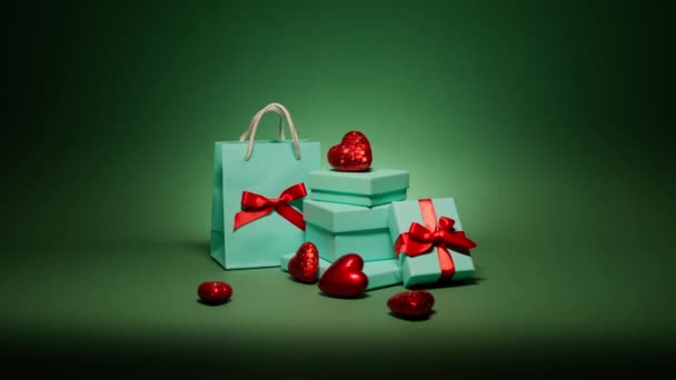 Muchas elegantes cajas de regalo azul azulado con corazones rojos aislados sobre hermoso fondo verde esmeralda de Navidad por la noche. Regalos sorpresa con joyas para aniversario de cumpleaños, Nochebuena, fiesta de Año Nuevo - Metraje, vídeo