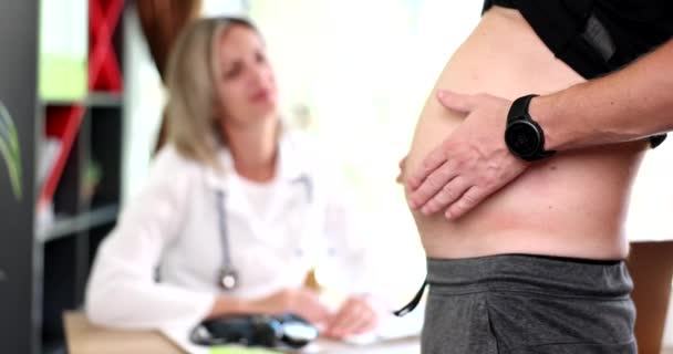 Γυναίκα γιατρός και άντρας ασθενής με λίπος στην κοιλιά. Ασθενής διαγνωστεί με διαβήτη λόγω παχυσαρκίας - Πλάνα, βίντεο
