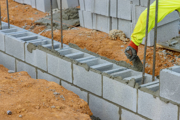 Οι χτίστες τοποθετούν τσιμεντόλιθους σε τοίχο για να κατασκευάσουν κτίριο χρησιμοποιώντας τσιμεντόλιθους. - Φωτογραφία, εικόνα