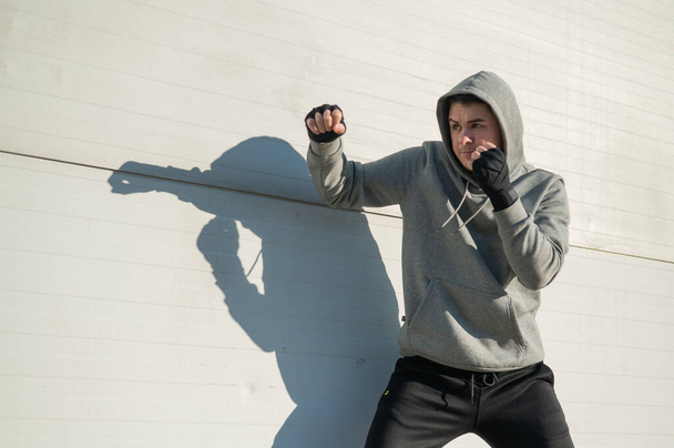 Caucasian man in hoodie is training boxing outdoors - Photo, image