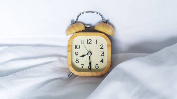Alarm hodiny v posteli s bílou přikrývkou pozadí - Fotografie, Obrázek