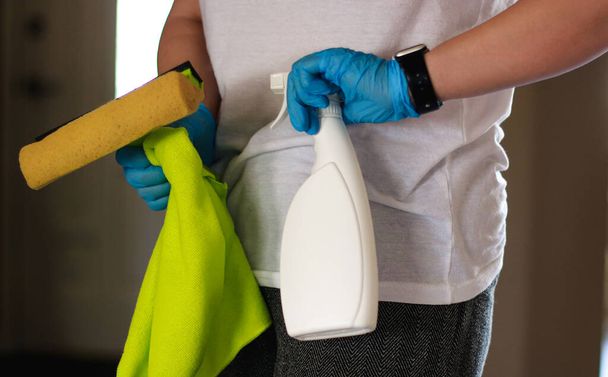 Frau mit Gummihandschuhen und Desinfektionsmittel, um ihre Wohnung zu säubern. Hochwertiges Foto - Foto, Bild