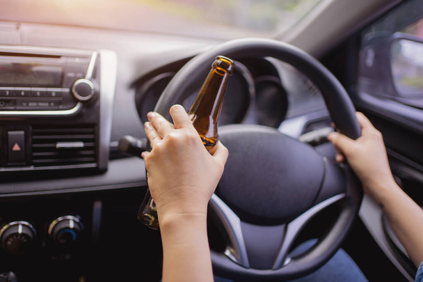 Concept of driving intoxicated, hand holding alcohol while driving. - Photo, Image