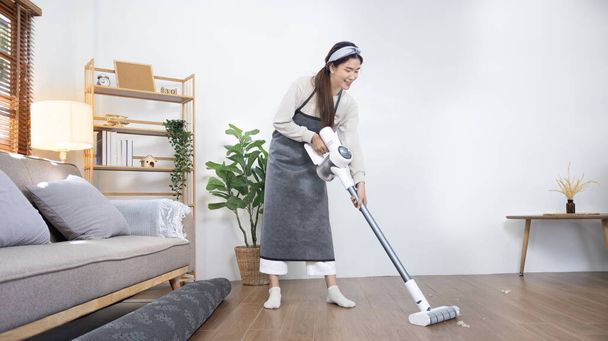 Krásná žena vysává podlahu a polštář svého obývacího pokoje, velký úklid v domě, odstraňuje bakterie a nečistoty a hluboké skvrny, úklid manželky v domácnosti, udržování její domov čistý, Domácí hygiena. - Fotografie, Obrázek