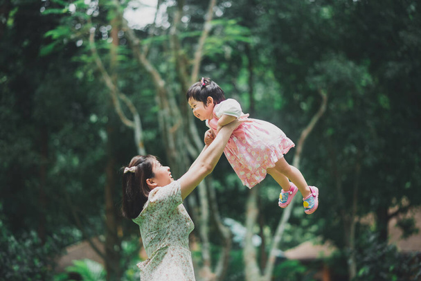 Asyalı mutlu anne kızını kucağına alıp sonbahar parkında iyi vakit geçiriyor. Aile kavramı. Baba ve çocuk kızı. Mutlu aile. - Fotoğraf, Görsel