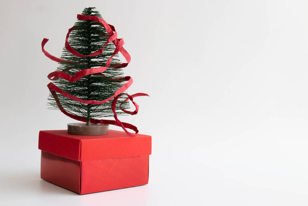 Χριστουγεννιάτικο Δέντρο για Διακόσμηση σε κόκκινο κουτί δώρου, τυλιγμένο με κόκκινη χάρτινη κορδέλα , - Φωτογραφία, εικόνα