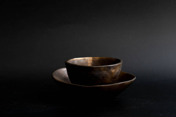 Nowoczesny kubek herbaty ze spodeczkiem, kolor miedzi, na czarnym tle - Zdjęcie, obraz