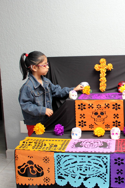 Mexican child girl put the altar and offering of the Day of the Dead in their house for their deceased relatives part of the tradition and culture of Mexico - Photo, Image