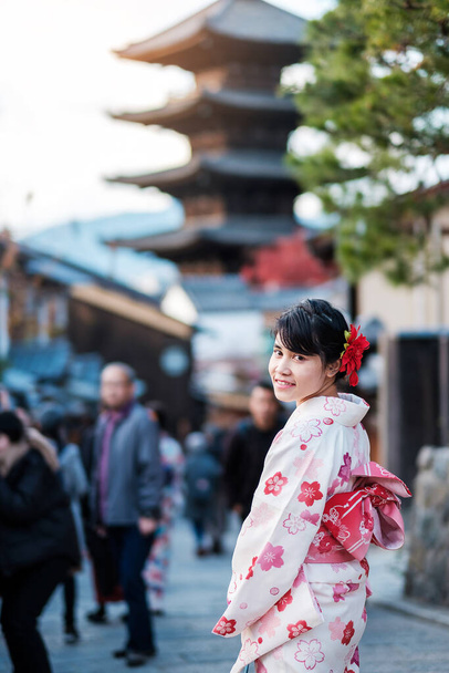 young woman tourist wearing kimono enjoy in Yasaka pagoda area near Kiyomizu dera temple, Kyoto, Japan. Asian girl with hair style in traditional Japanese clothes in Autumn foliage season - Photo, Image