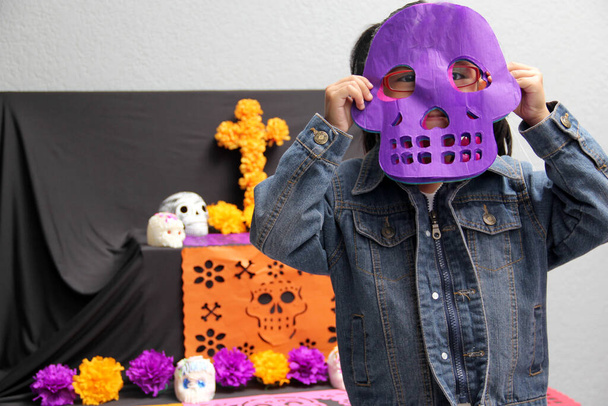 Mexikanisches Mädchen stellte den Altar und die Opfergabe des Tages der Toten in ihr Haus für ihre verstorbenen Verwandten, die Teil der Tradition und Kultur Mexikos sind - Foto, Bild
