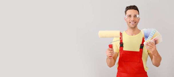 Male painter with roller and color samples on light background with space for text - Foto, afbeelding