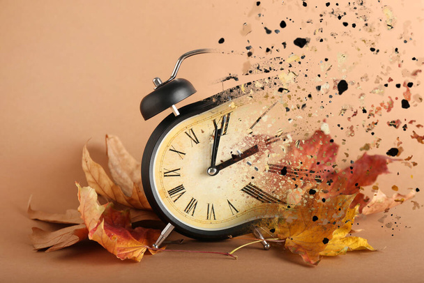 秋の葉が茶色の背景で目覚まし時計を粉砕 - 写真・画像
