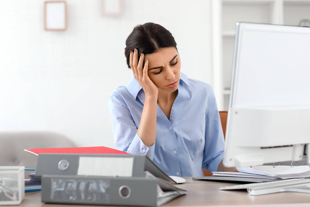 Stressed young businesswoman sitting at table in office - Photo, Image