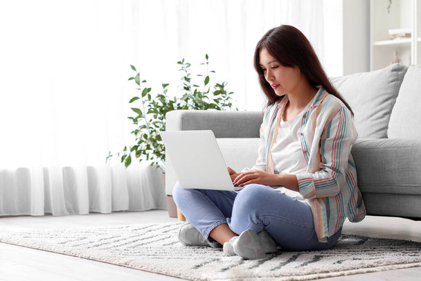 Young Asian woman using laptop on floor at home - Foto, imagen