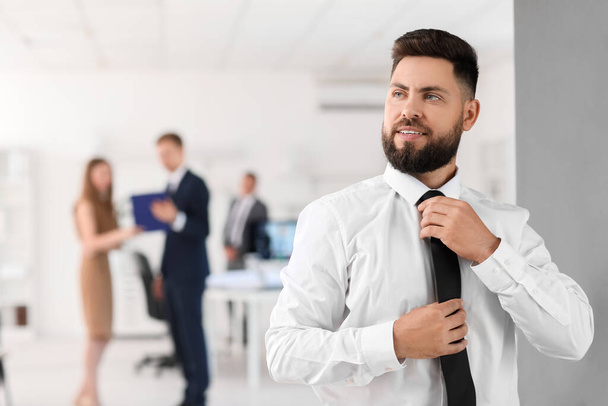 Guapo banco manager ajustando corbata en oficina - Foto, Imagen