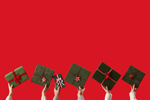 People with Christmas presents on red background - Photo, Image