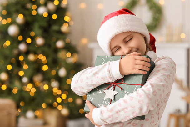 Šťastná holčička v santa klobouk s vánoční dárek doma - Fotografie, Obrázek