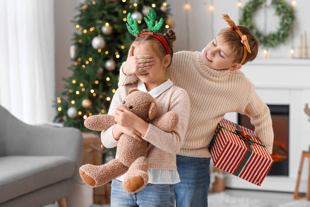Petit garçon surprenant sa sœur avec un cadeau de Noël à la maison - Photo, image