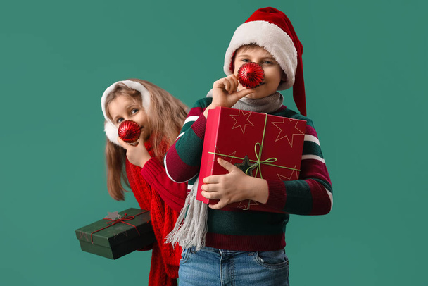 Malé děti s vánoční koule a dárky na zeleném pozadí - Fotografie, Obrázek
