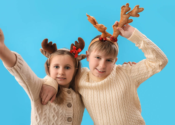 Little children in reindeer horns on blue background - Photo, Image
