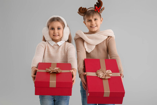 Μικρά παιδιά με χριστουγεννιάτικα δώρα σε γκρι φόντο - Φωτογραφία, εικόνα