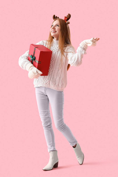 fiatal nő rénszarvas szarvak karácsonyi ajándék rózsaszín háttér - Fotó, kép