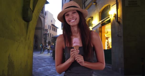 Mulher turística feliz na rua Florença com cone de sorvete, sorrindo para a câmera. Elegante menina caucasiana de férias na Itália desfrutando de gelato de morango. 4k - Filmagem, Vídeo