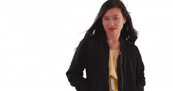 Mulher fresco quadril milenar vestindo jaqueta preta isolada no fundo branco. Retrato de jovem senhora asiática com o cabelo soprando no vento para espaço de cópia. 4k - Filmagem, Vídeo
