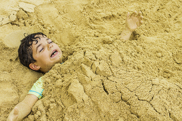 Fiatal fiú eltemetett a homok - Fotó, kép