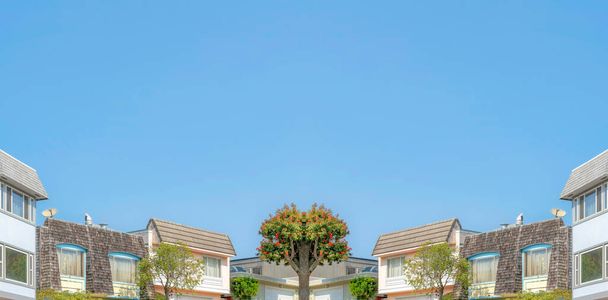 Abstract gespiegelde achtergrond Low angle view of suburban houses with wood vinyl and shingle sidings at San Francisco, California. Buurt met twee verdiepingen huizen tegen de heldere blauwe lucht. - Foto, afbeelding
