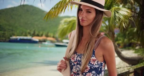 Retrato de mujer atractiva en traje de verano en un entorno de playa tropical. Mujer atractiva con estilo en sus años 20 vistiendo sombrero y mameluco en la playa tropical. 4k - Metraje, vídeo