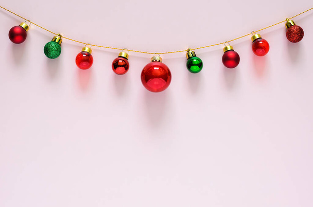 Πολύχρωμο στολίδι στολίδια Χριστούγεννα κρέμονται στην κορυφή με ροζ φόντο. Ελάχιστη έννοια διακοπών. - Φωτογραφία, εικόνα