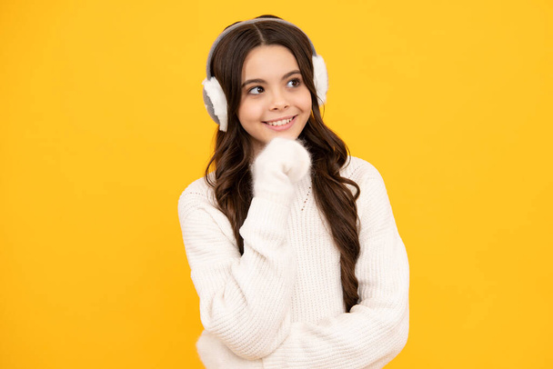 Modern teen girl wearing sweater and winter warm earmuff ear-flaps hat on isolated yellow background - Foto, immagini