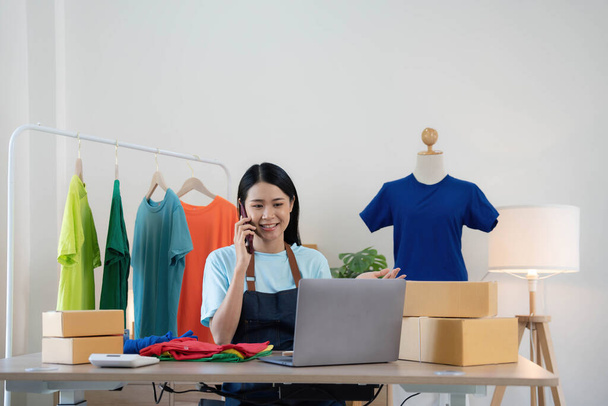 Piękna azjatycka kobieta sprzedawca online potwierdzające zamówienia od klienta przez telefon, Start małe firmy właściciele MŚP kobiety przedsiębiorcy korzystać z laptopa w domu, opakowanie i koncepcja sytuacji dostawy.. - Zdjęcie, obraz