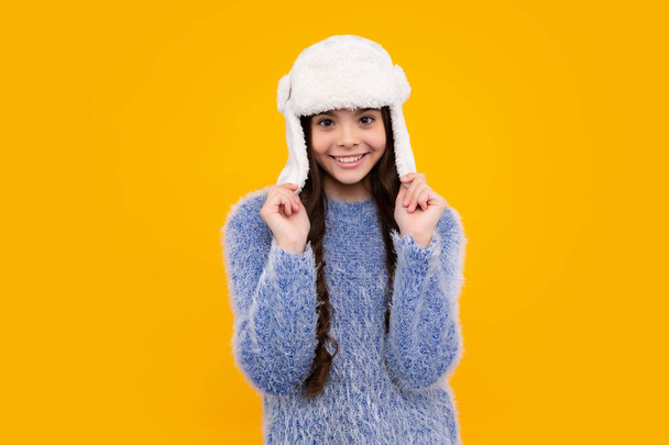 Teenager girl with winter hat over isolated yellow background. Winter christmas holidays, new year mood. Kids warm clothes. Happy teenager, positive and smiling emotions of teen girl - Photo, Image