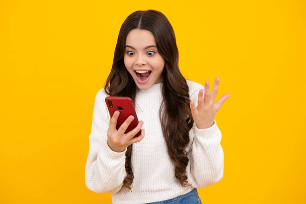 Teenager child girl holding smartphone. Hipster girl with cell phone. Kid hold mobile phone texting in online social networks. Excited teenager girl - Foto, Imagem